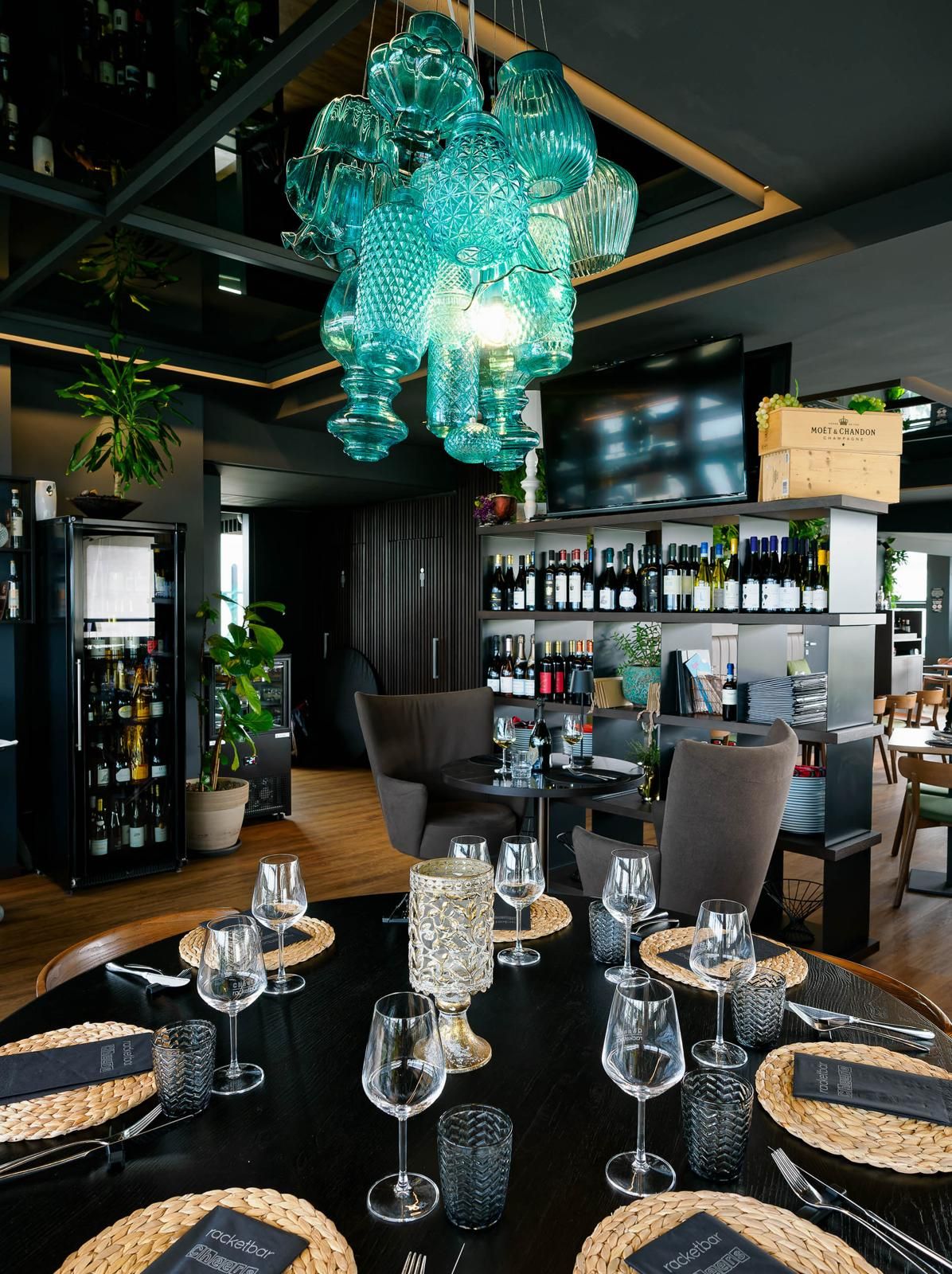 La sala del cheers con il lampadario turchese e la parete dei vini