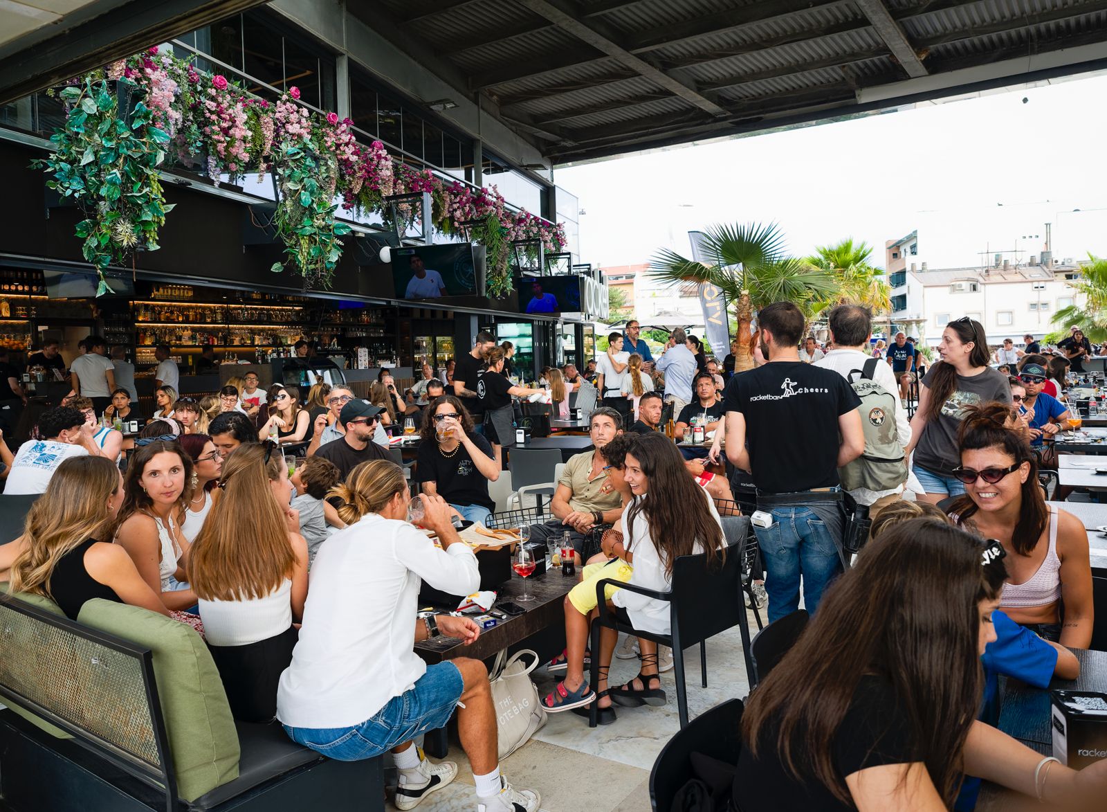 Il dehors del racket bar pieno di gente sotto la pergola